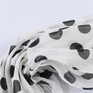 Gros plan sur un tissu en mousseline blanche à pois noirs et texture plissée