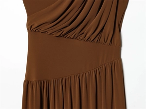 Détail du drapé asymétrique et de la texture plissée sur une robe longue marron