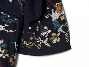 Detailed close-up of colorful floral embroidery and hollow lace on navy blouse sleeve