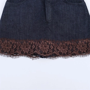 Dettaglio di gonna in denim blu scuro con pizzo floreale marrone e bordo a frange