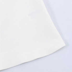 Détail de l'ourlet de la robe blanche montrant les coutures plates et le grain du tissu