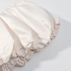 Gros plan du détail des manches bouffantes en satin blanc perle avec texture plissée élégante