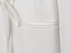 Macro view of white linen blend blazer featuring diagonal twill texture and welt pocket detail