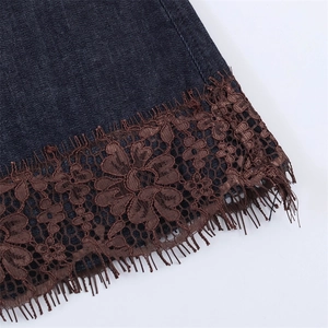 Dettaglio dell'orlo in denim con pizzo floreale marrone e rifiniture di frange sottili