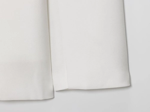 Close-up detail of white linen blend fabric texture and professional stitching on blazer