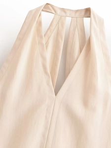 Gros plan du haut dos nu avec décolleté en V et coutures fines sur tissu beige texturé
