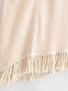 Gros plan sur l'ourlet à franges beige et le tissage du pantalon large en lin