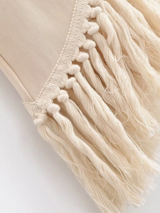 Détail de glands en coton crème et nœuds tissés sur l'ensemble haut et pantalon large beige