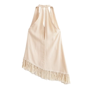 Détail du haut dos nu beige avec décolleté en V profond et ourlet asymétrique à franges