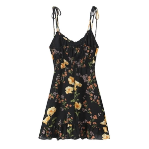 Detail of floral printed summer dress featuring smocked waist and bow tie straps