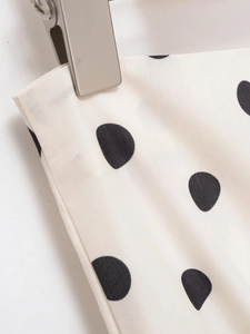 Detaillierte Nahaufnahme von weißem Polka-Dot-Stoff mit schwarzem Druck und Nähten