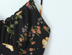 Detail of floral printed dress with ruffles and thin shoulder straps on white background