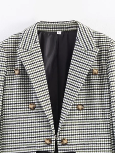 Detail of green and black houndstooth blazer with double-breasted buttons and peaked lapels