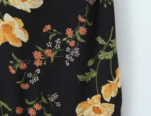 Detailed macro view of the floral print fabric with yellow flowers on black chiffon base
