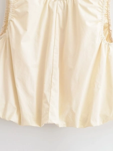 Détail d'un haut sans manches blanc cassé avec poignets élastiques froncés et texture
