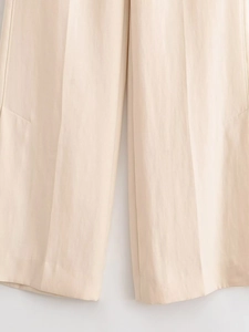 Détail du pantalon large crème montrant la texture tissée et le pli central marqué
