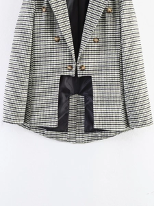 Detail of houndstooth blazer with double-breasted buttons and asymmetric cutout hem
