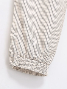Détail du poignet en nylon à carreaux avec bouton en métal argenté et finition élastique