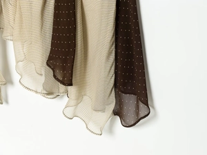 Detail view of polka dot chiffon fabric with asymmetric ruffled stitching and sheer texture