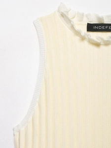 Detail of ruffle neckline and ribbed texture on sleeveless beige knitted top