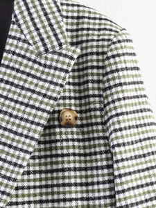 Close-up of green plaid blazer texture showing button detail and houndstooth pattern