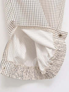 Vue macro détaillée de l'ourlet du pantalon à carreaux beige avec élastique et bouton pression