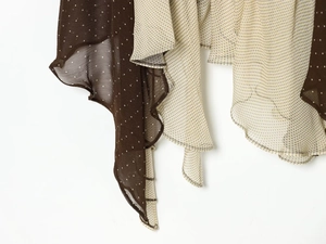 Detail of asymmetrical ruffled hem on polka dot chiffon dress in brown and cream