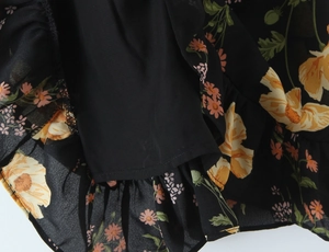 Close-up of floral print dress fabric with yellow flowers and ruffled hemline detail