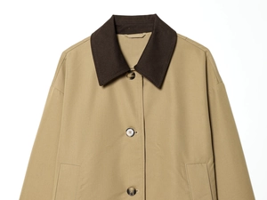Detail of khaki cropped trench coat featuring contrast corduroy collar and marbled buttons