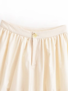 Détail de la taille d'une jupe ivoire avec bouton et plis délicats sur le devant