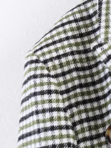 Macro detail of French vintage asymmetric plaid blazer fabric with amber button