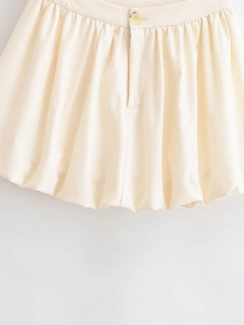 Gros plan sur la jupe boule beige avec plis à la taille et détail bouton rétro unique