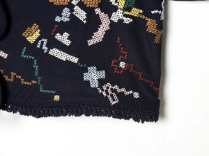 Macro shot of colorful floral embroidery and delicate dark blue lace trim on fabric