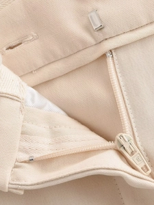 Détail de la fermeture à crochet métallique et du zip beige assorti sur le pantalon