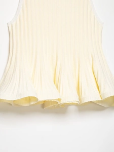 Detail of ribbed knit top featuring a ruffled hem and vertical striped texture in cream