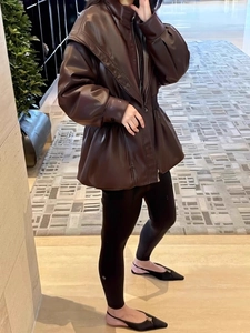 Dettaglio giacca oversize in ecopelle marrone scuro con cappuccio e coulisse al fondo