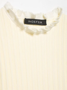 Macro detail of creamy ribbed knit fabric with white ruffle collar and brand label