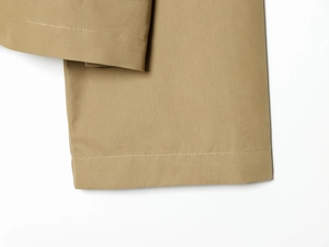 Detailed close-up of khaki cotton trousers hem featuring precise stitching and high-density fabric