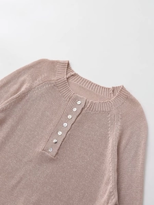 Detail of grey-pink knit sweater featuring a round henley neck and pearlescent buttons
