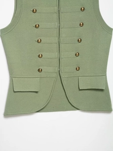 Close-up of sage green knit vest featuring antique bronze buttons and flap pockets