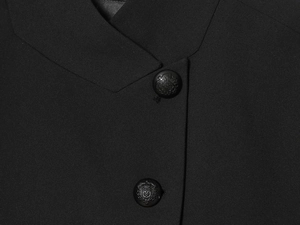 Detail of high-quality black twill blazer featuring embossed crest buttons and collar texture