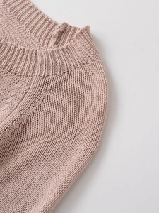 Detailed close-up of ribbed crew neck and fine knit texture on a dusty pink sweater