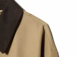 Detailed close-up of khaki twill fabric shoulder seam and contrasting dark brown collar