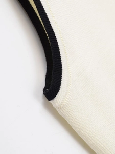 Detailed macro view of cream knitted vest with contrasting black ribbed trim on sleeve