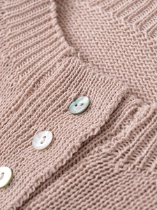 Close-up of pink knit cardigan showing fine texture and pearlescent shell buttons