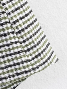 Detailed close-up of green and white tweed fabric texture showing premium weave quality