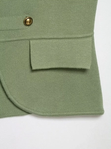 Detail of sage green knitted vest with vintage gold button and flap pocket detail