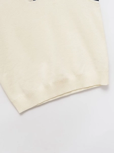 Close-up of cream knit vest showing detailed stitching and ribbed hem for a snug fit