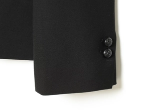Detailed close-up of a black blazer sleeve featuring ornate equestrian crest buttons