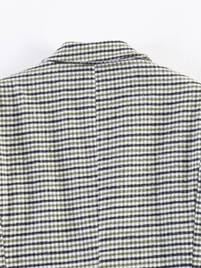 Macro shot of green houndstooth wool fabric texture and stitching on the collar of a blazer